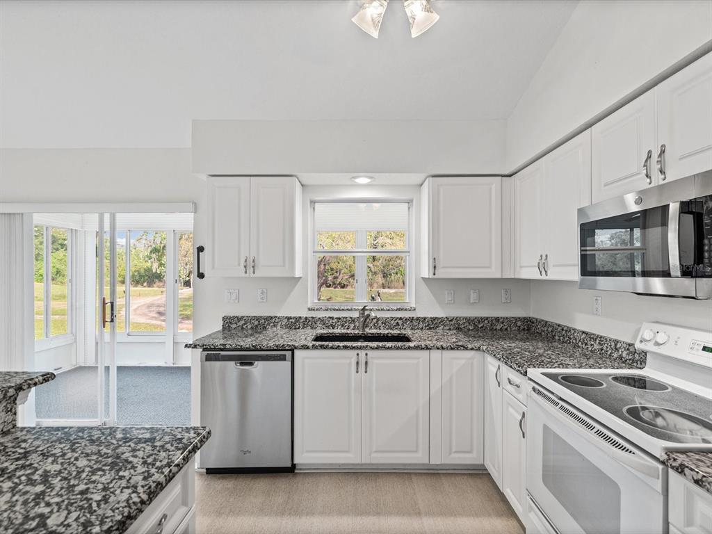 11621 Holly Ann Drive New Port Richey, FL 34654 - Photo 15 of 59 a kitchen with stainless steel appliances granite countertop a stove a sink and a white cabinets