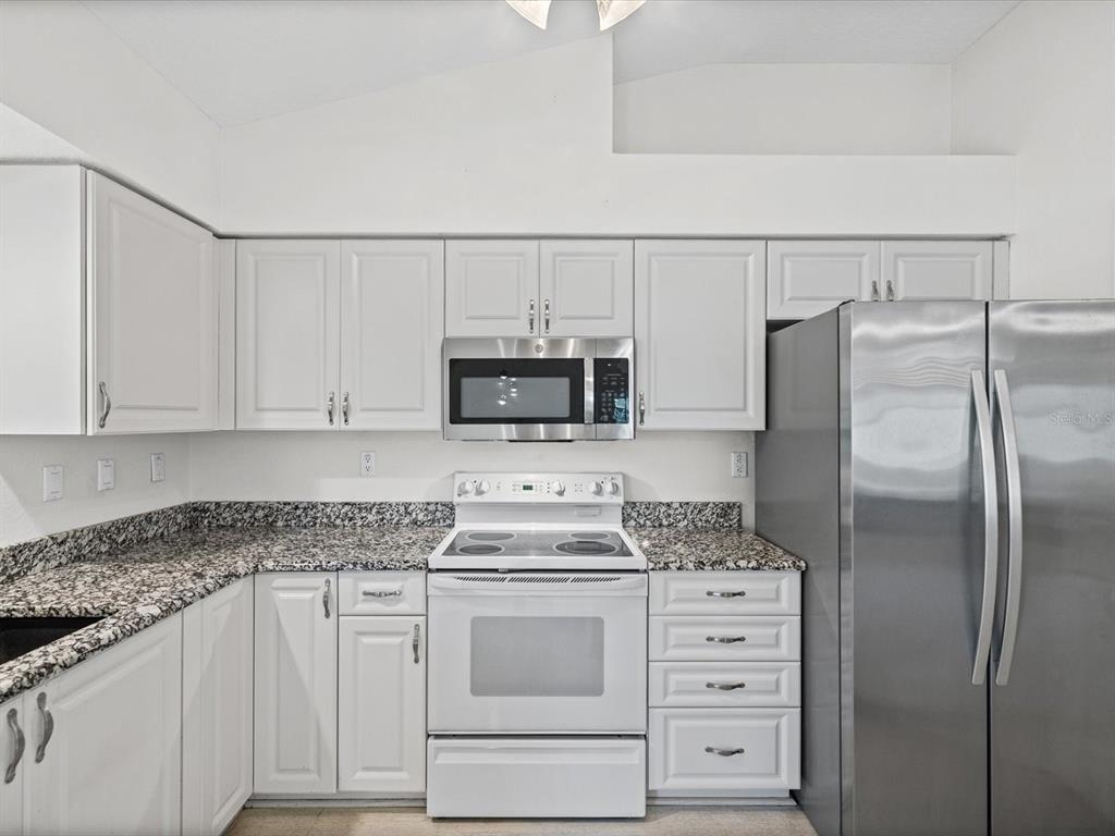 11621 Holly Ann Drive New Port Richey, FL 34654 - Photo 16 of 59 a kitchen with white cabinets and stainless steel appliances
