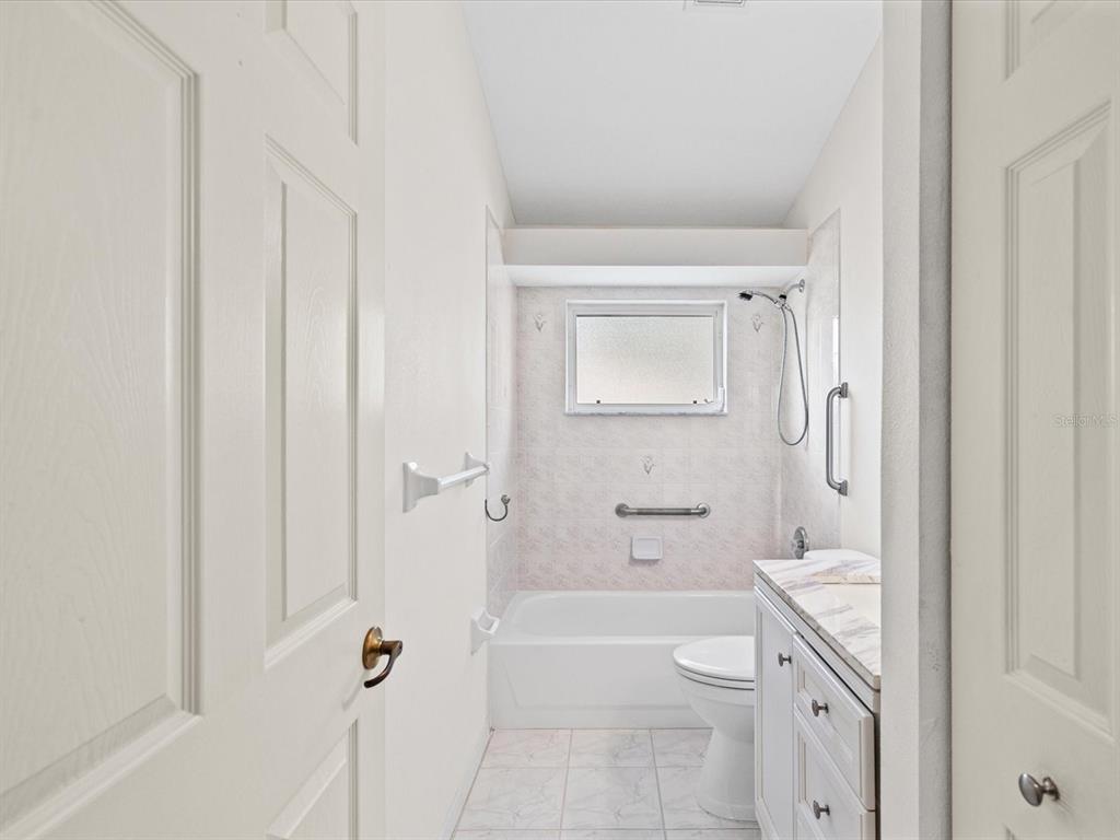 11621 Holly Ann Drive New Port Richey, FL 34654 - Photo 22 of 59 a bathroom with a granite countertop toilet a sink and bathtub