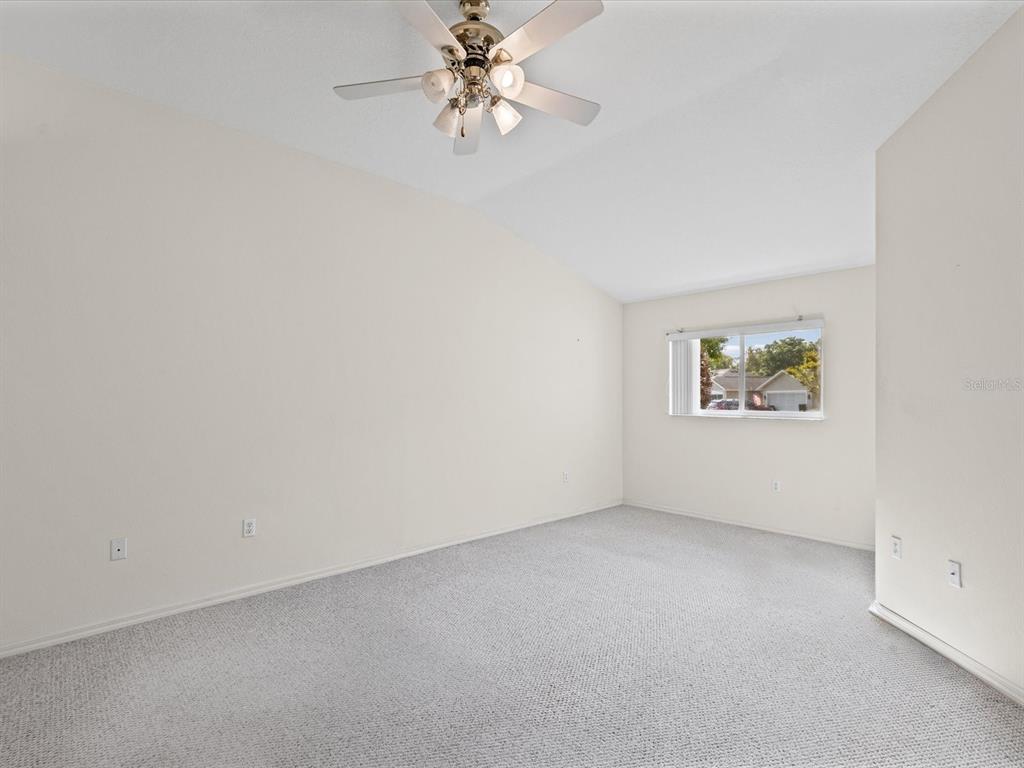 11621 Holly Ann Drive New Port Richey, FL 34654 - Photo 26 of 59 an empty room with a chandelier fan and windows
