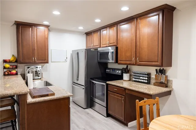 a kitchen with stainless steel appliances granite countertop a refrigerator a stove a sink and a microwave