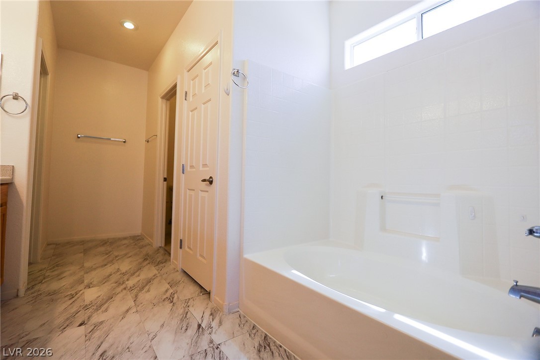 6472 Centennial Road Pahrump, NV 89048 - Photo 8 of 29 Indulge in a tranquil bathing experience within this well-appointed bathroom, featuring a deep soaking tub and marble-inspired tile flooring.