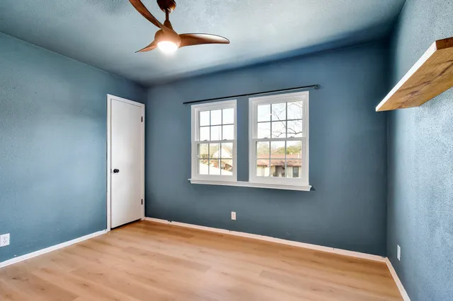 a view of a big room with windows and chandelier fan