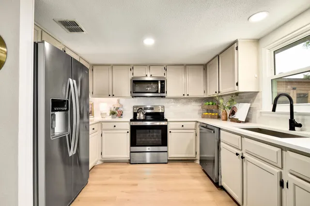 a kitchen with cabinets stainless steel appliances and a window