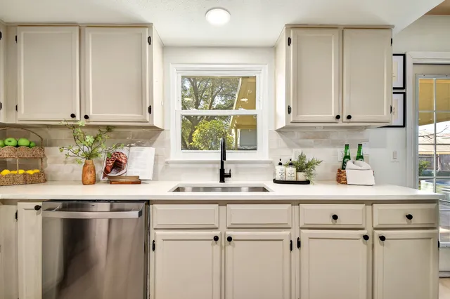 a kitchen with stainless steel appliances white cabinets a window and a sink
