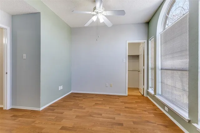 a view of an empty room with window and wooden floor