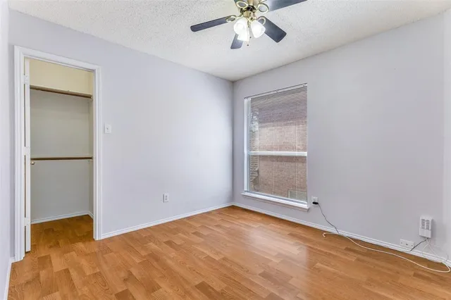 an empty room with a chandelier fan and windows