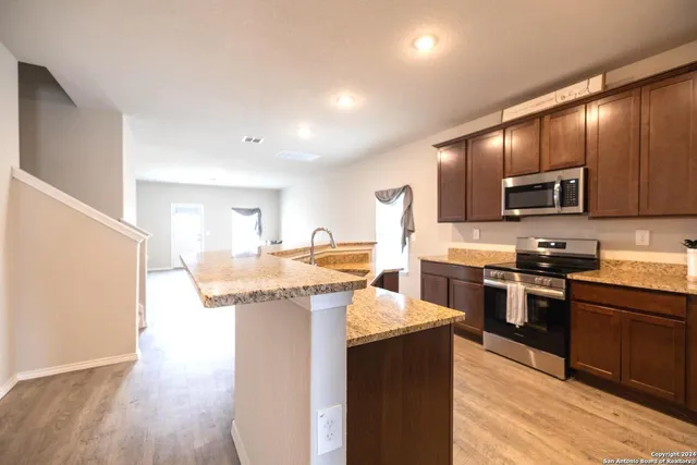 a kitchen with kitchen island granite countertop wooden floors and stainless steel appliances