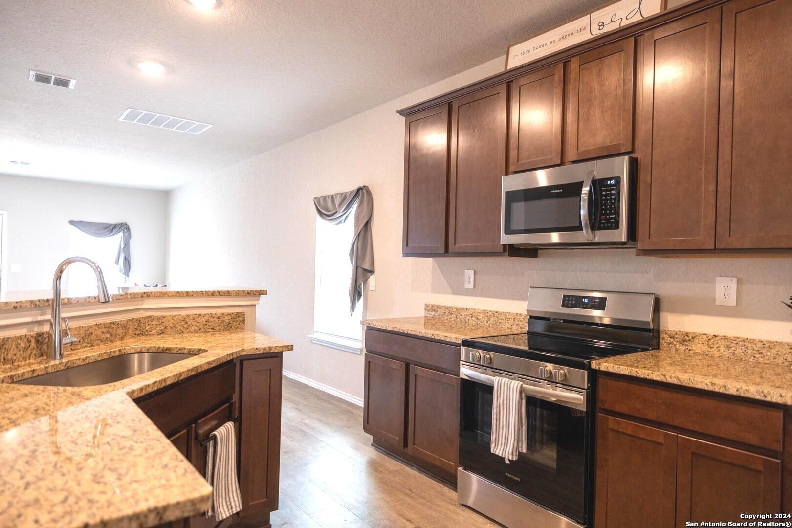 3431 Andromeda Way Converse, TX 78109 - Photo 7 of 24 a kitchen with stainless steel appliances granite countertop a sink stove and microwave
