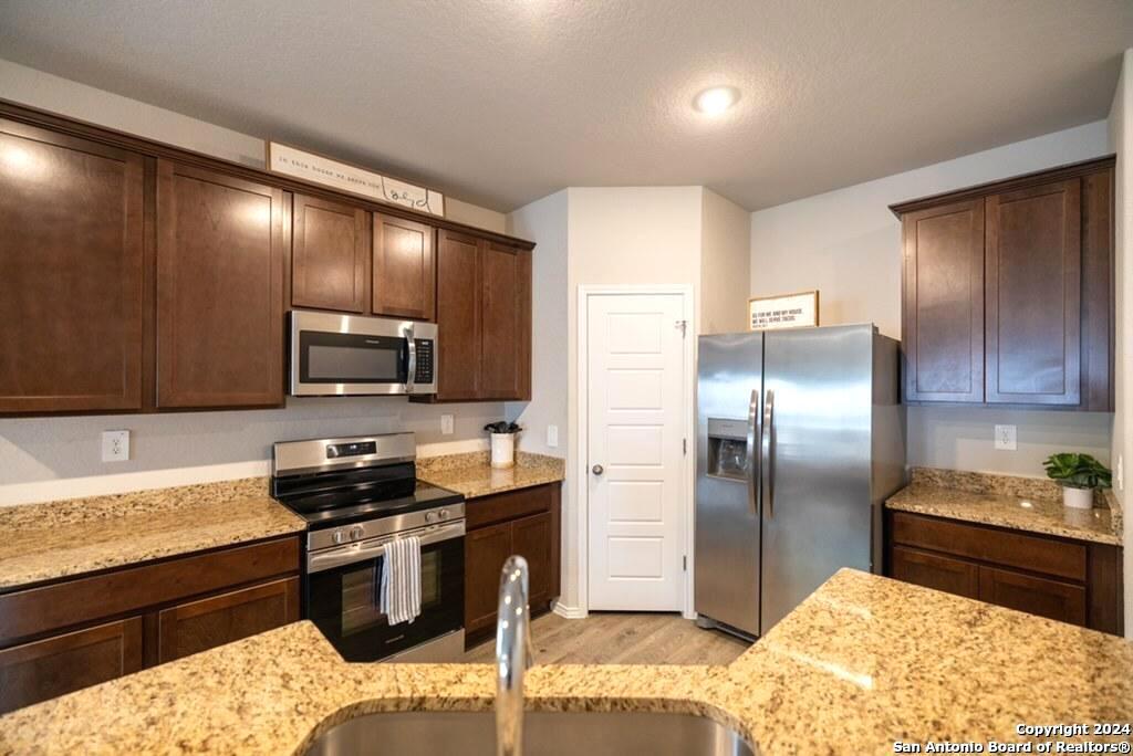 3431 Andromeda Way Converse, TX 78109 - Photo 8 of 24 a kitchen with granite countertop stainless steel appliances and wooden cabinets