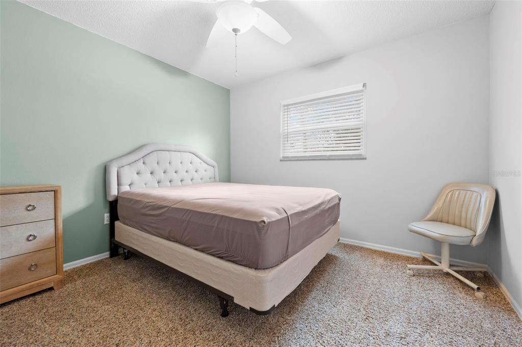 11244 Redgate Street Spring Hill, FL 34609 - Photo 28 of 50 a bedroom with a bed chair and a lamp on dresser