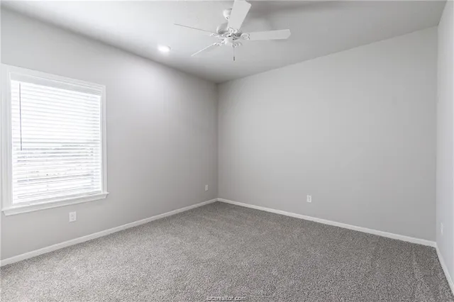 an empty room with a window and a fan