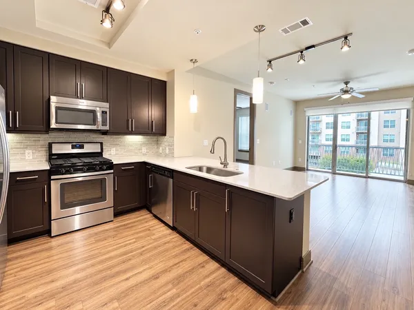 a kitchen with stainless steel appliances kitchen island granite countertop a sink and wooden cabinets
