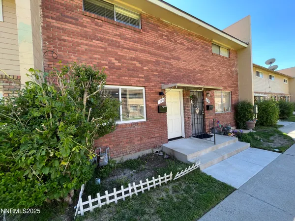 a view of a house with brick walls and a yard with plants