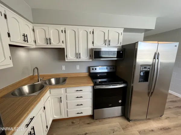 a kitchen with stainless steel appliances granite countertop a refrigerator a stove and white cabinets