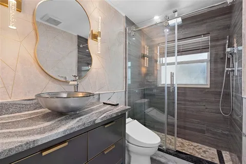 a bathroom with a granite countertop sink a toilet and shower