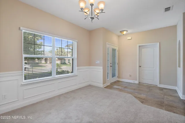 an empty room with chandelier fan and windows