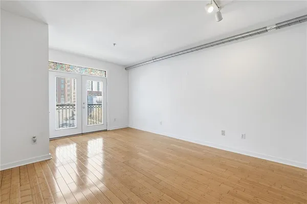 a view of an empty room with wooden floor and a window