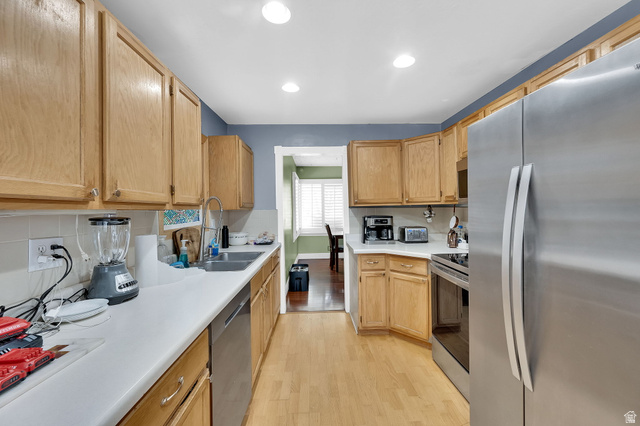4635 Box Elder Street Murray, UT 84107 - Photo 9 of 21 Kitchen with stainless steel appliances, light countertops, light wood finished floors, light wood finish cabinetry, and backsplash