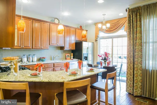 a kitchen with granite countertop a table chairs stove and wooden cabinets