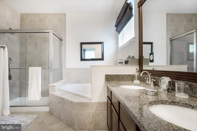 a bathroom with a granite countertop bathtub a sink and a mirror
