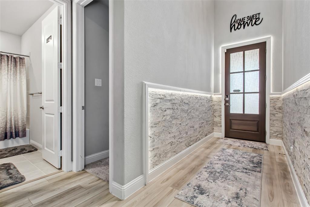 2437 Pinnacle Place Corinth, TX 76210 - Photo 4 of 40 a view of a hallway with wooden floor and a bedroom