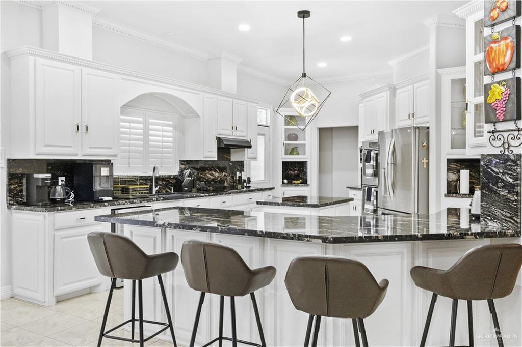 800 East Mile 3 Road Mission, TX 78573 - Photo 9 of 45 a kitchen with stainless steel appliances granite countertop a stove a sink dishwasher a refrigerator white cabinets and chairs with wooden floor