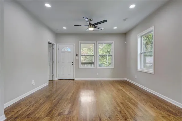 an empty room with wooden floor and windows