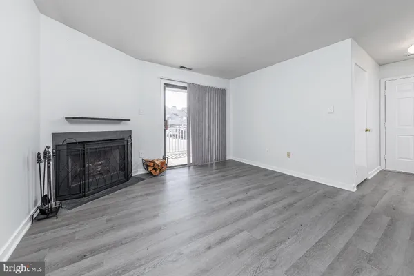 an empty room with wooden floor fireplace and windows