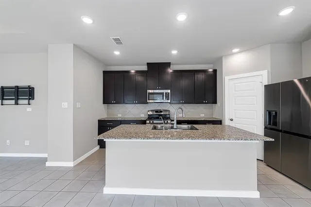 a kitchen with kitchen island stainless steel appliances a sink and a refrigerator