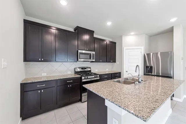a kitchen with stainless steel appliances granite countertop a sink stove and refrigerator