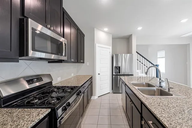 a kitchen with granite countertop stainless steel appliances a sink cabinets and a stove top oven