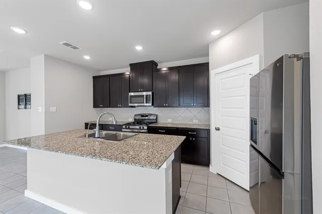 a kitchen with stainless steel appliances granite countertop a sink stove and refrigerator