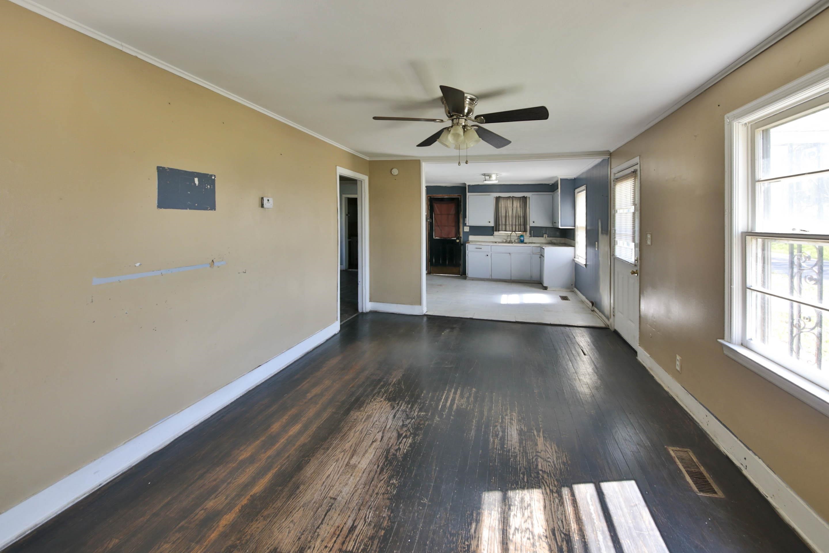 322 Highland Street Ripley, TN 38063 - Photo 8 of 12 Unfurnished living room featuring dark wood-style floors, a ceiling fan, and ornamental molding