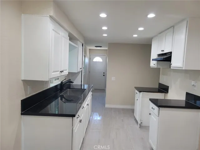 a kitchen with granite countertop a sink and white cabinets