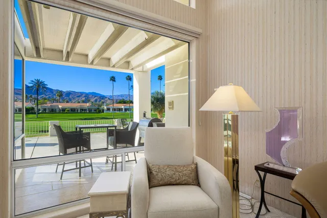 a living room with furniture a lamp and a floor to ceiling window