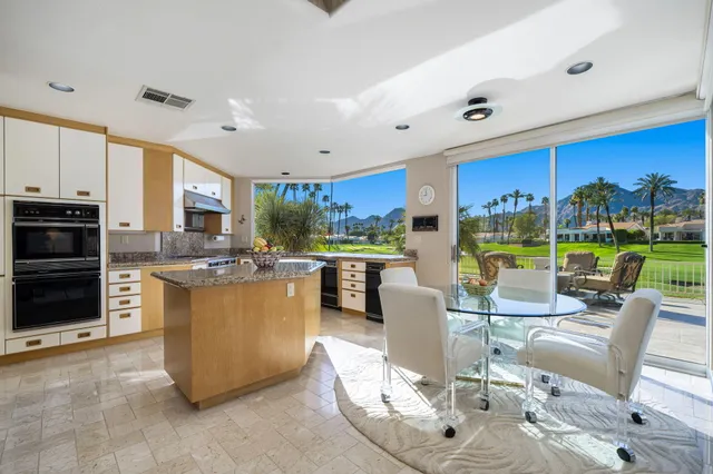 a living room with patio furniture and a kitchen view