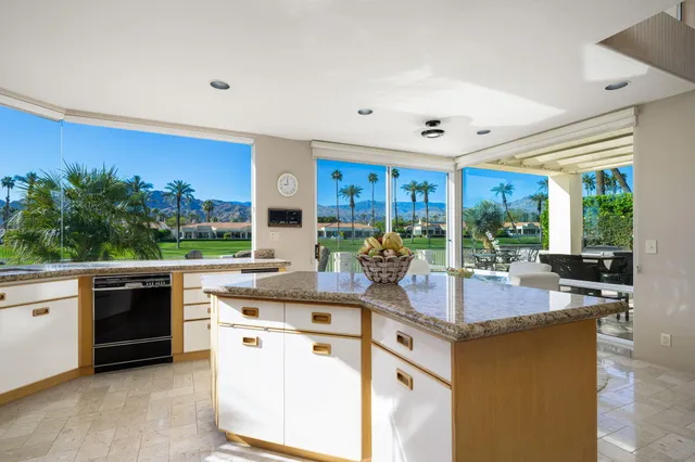 a kitchen with kitchen island granite countertop white cabinets and stainless steel appliances