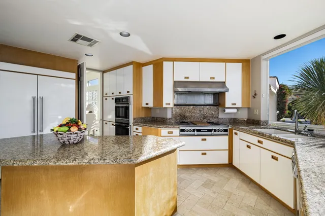 a kitchen with stainless steel appliances granite countertop a sink a stove and a wooden floors