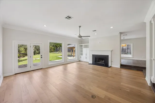 a view of an empty room with window and wooden floor