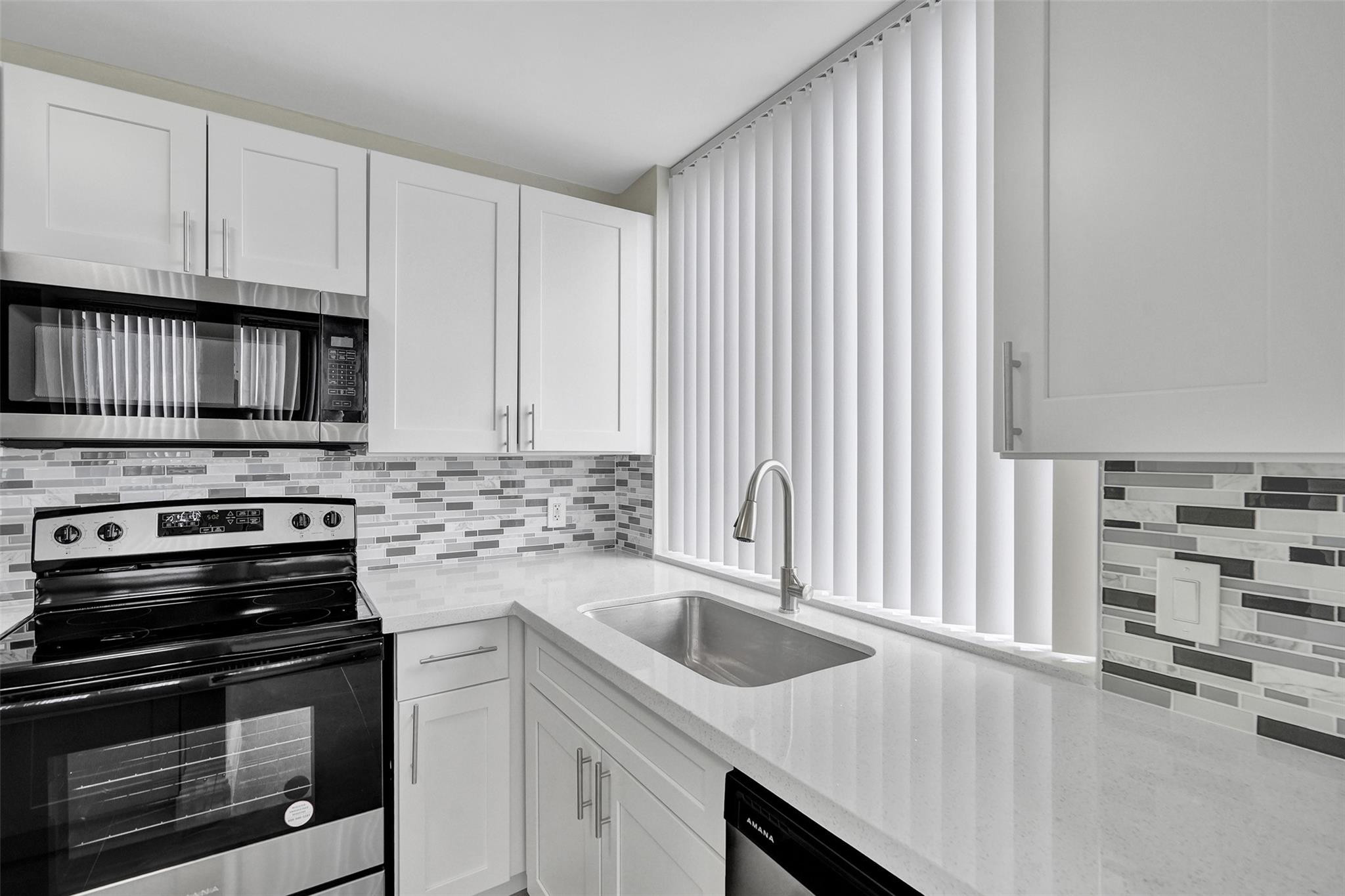 4222 Inverrary Boulevard, Unit 4810 Lauderhill, FL 33319 - Photo 13 of 63 a kitchen with granite countertop a stove and a sink