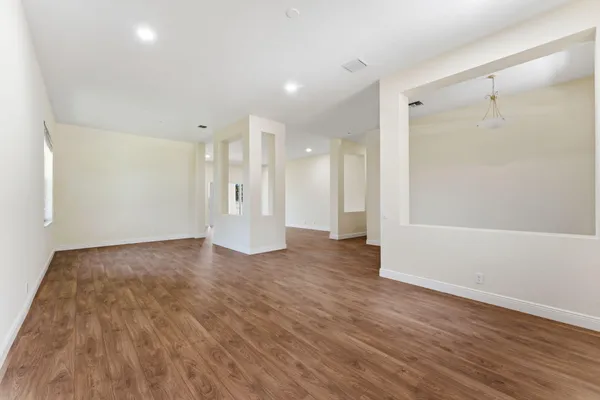 a view of a big room with wooden floor and windows
