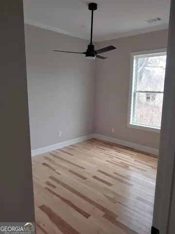 a view of empty room with wooden floor and fan