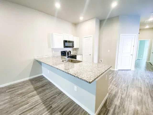 a kitchen with granite countertop a sink and a stove top oven