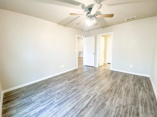 an empty room with wooden floor and windows