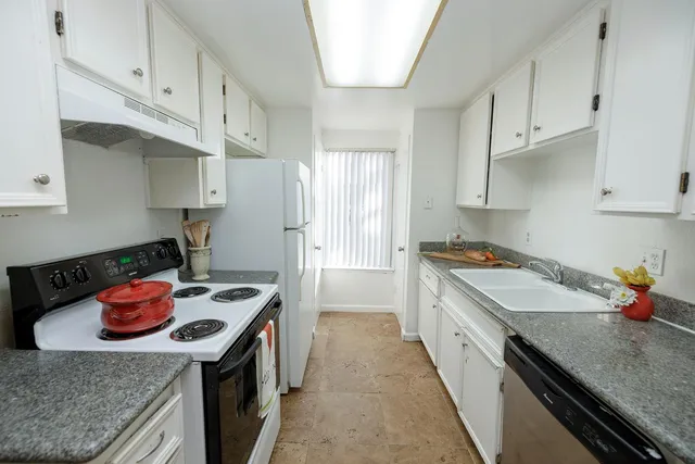 a kitchen with stainless steel appliances granite countertop a stove a sink a refrigerator and wooden cabinets