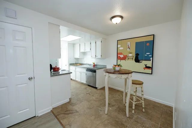 a kitchen with white cabinets and chairs