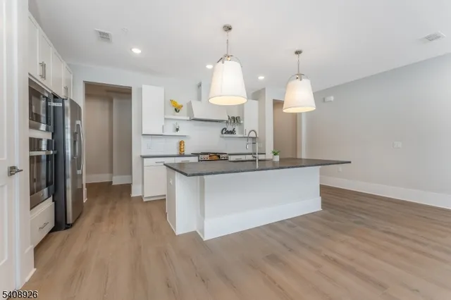 a view of kitchen with granite countertop refrigerator stove and wooden floor