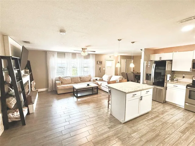 a living room with stainless steel appliances kitchen island granite countertop a stove and a refrigerator
