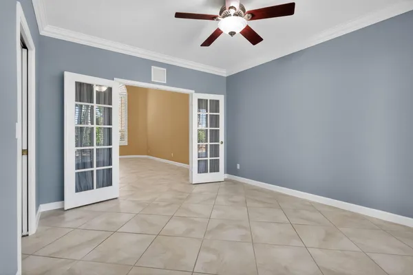 a view of an empty room with a window and chandelier fan
